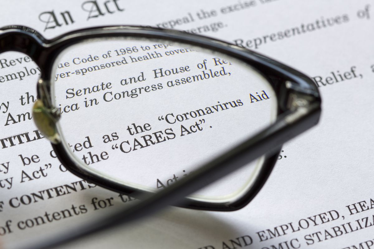 Text of the CARES Act seen through the lens of a pair of glasses resting on the document.